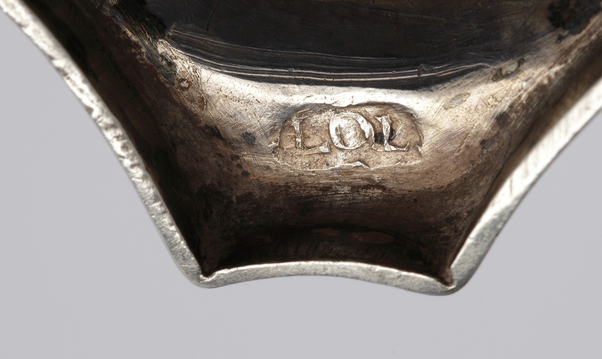 S.k. supkalk av silver, med ben och fot. 
Graverat mönster på skålens kant och på foten. Invändigt är cuppan förgylld. Foten är åttkantig. 
Stämplar (deformerade, svårtydda) i botten. 

Inskrivet i huvudkatalogen 1963.