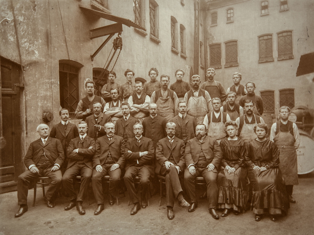 Damman og Baltzersens eiere og personale, 1890. 
Bildet er tatt på gårdsplassen i Kongensgate 4 i Kristiania. 