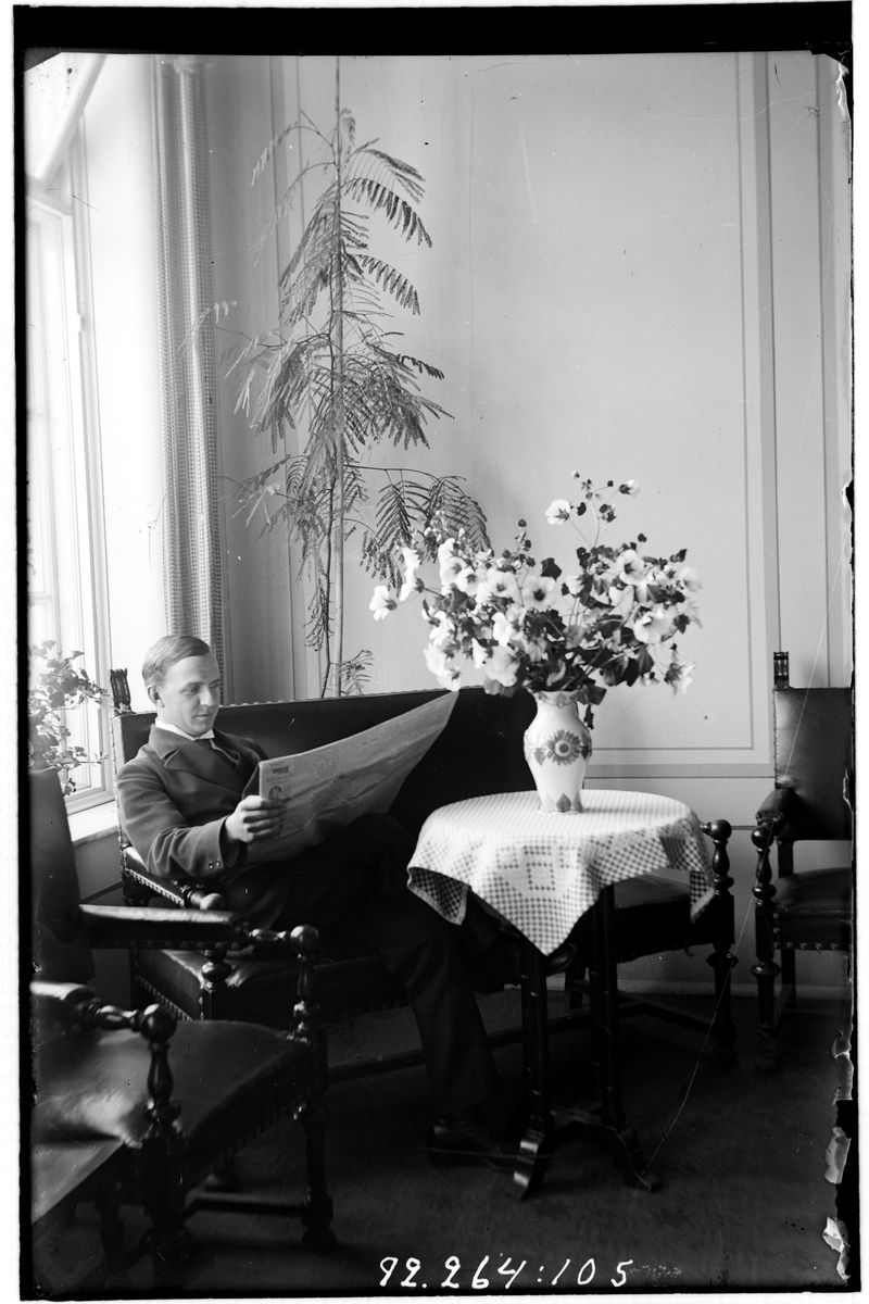 Hålahult sanatorium, interiör, en man sitter på en soffa vid ett bord och läser tidningen.