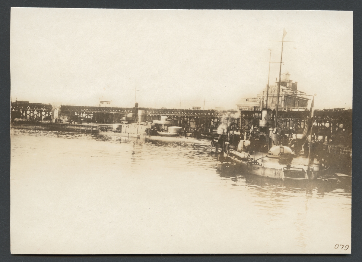 Bilden visar hamnbassäng i Odessa med ett flertal örlogsskepp som ligger förtöjt vid kajen. I bakgrunden syns en stor träbro.

Originaltext: "Krigsskepp, tillhörande K. K. Donau-flottiljen i Odessas hamn."