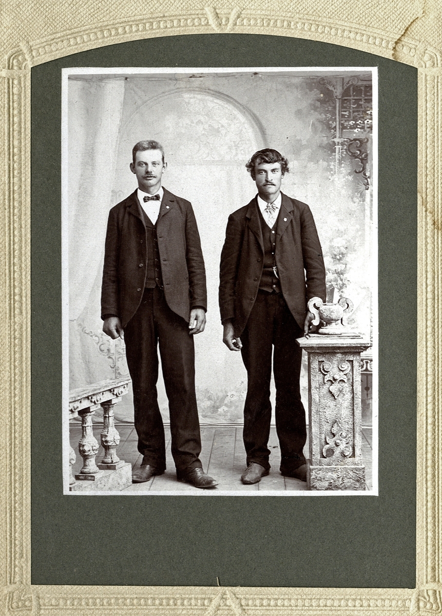Foto av två unga män i kostym med stärkkrage och fluga. På baksidan står antecknat: "1908". 
Helfigur, en face. Ateljéfoto.