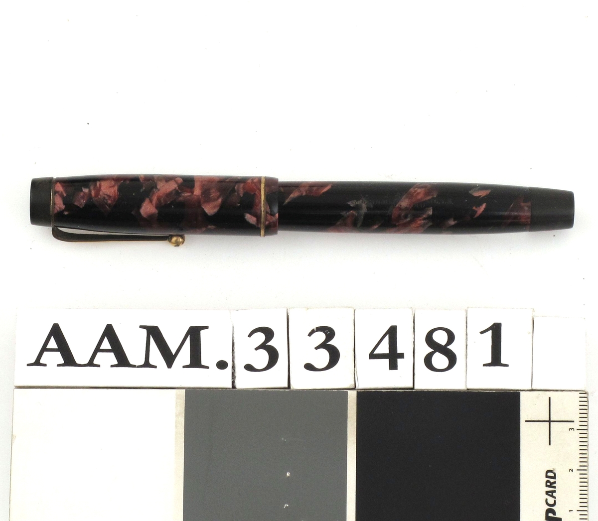 Fyllepenn, sort med mønster i rosavalører.
Pennen inneholder en beholder og blekk suges opp i beholderen fra et blekkhus.
