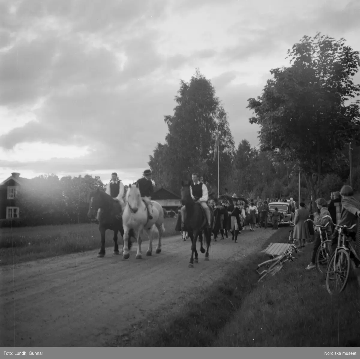 Motiv: (ingen anteckning) ;
En kvinna och två män spelar boccia, porträtt av en kvinna i folkdräkt, en folksamling står vid en gärsgård, tre män i folkdräkt rider på hästar framför män som spelar fiol och kvinnor i folkdräkt som går på en väg "Midsommartåget till Tibble", en kvinna i folkdräkt rider på en häst som drar en vagn med barn, kvinnor och män pryder en midsommarstång med lövade ringar.dju
