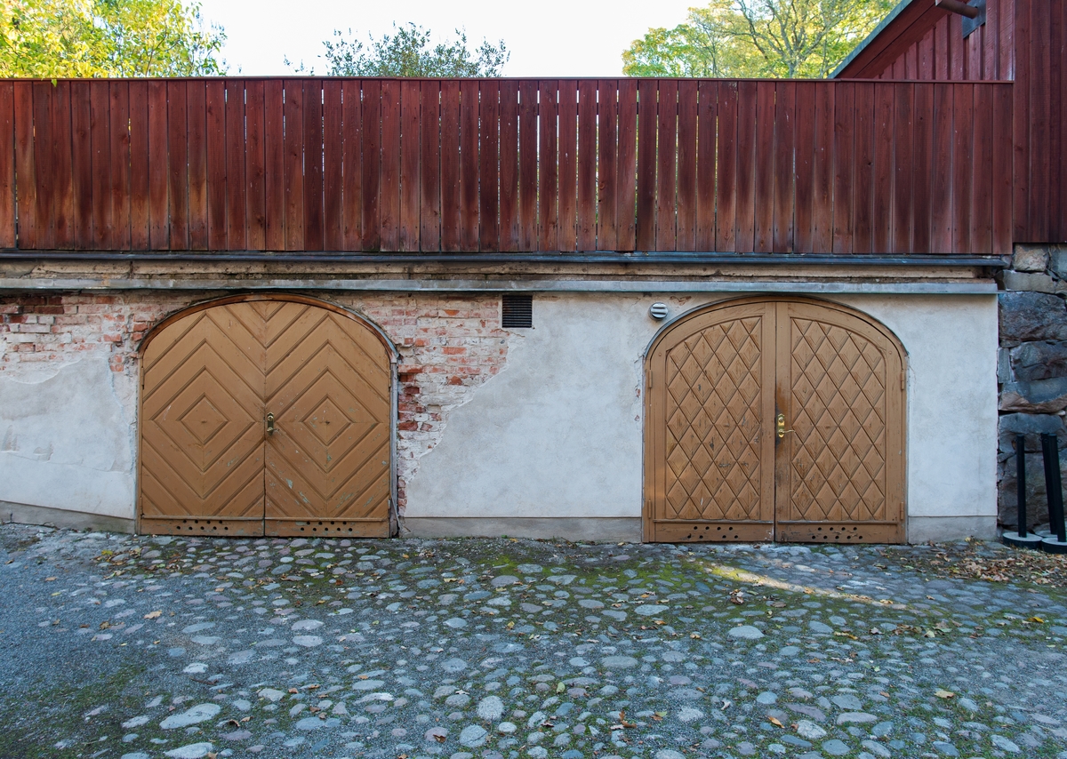 Garaget under Petissans gård är en putsad tegelmurad byggnad med betongpelare. Fasaden är vit och domineras av två rundbågiga portar med gula dörrar av trä. Byggnadens tak består av Petissans gård med uteservering.