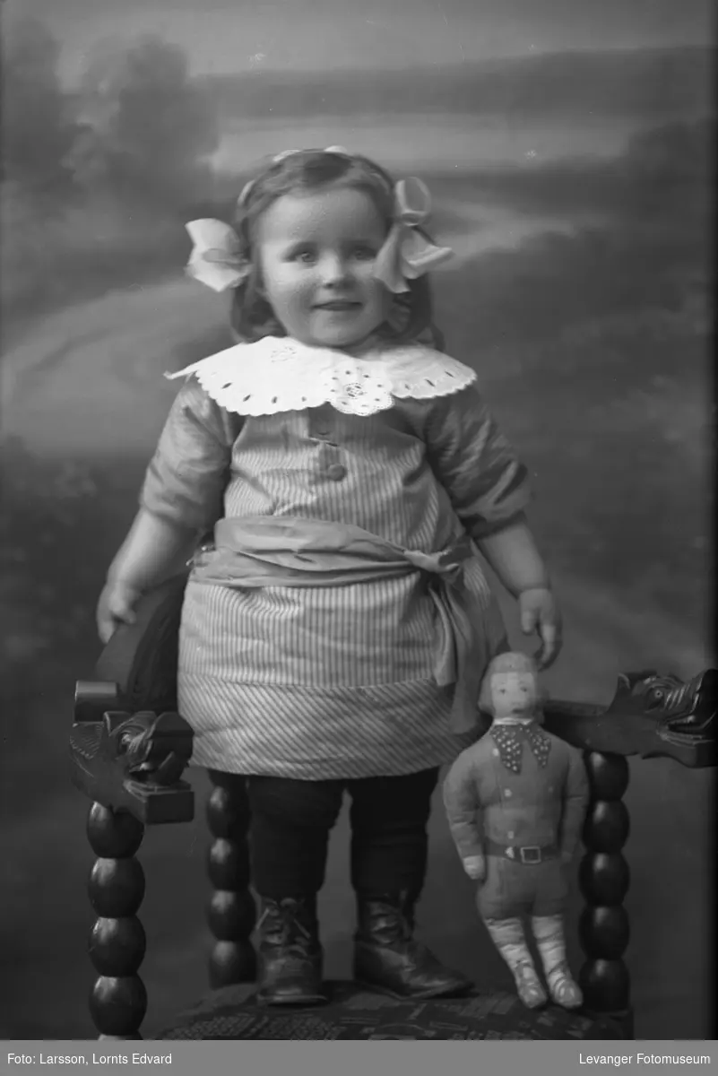 Portrett av ei lita jente med dukke.