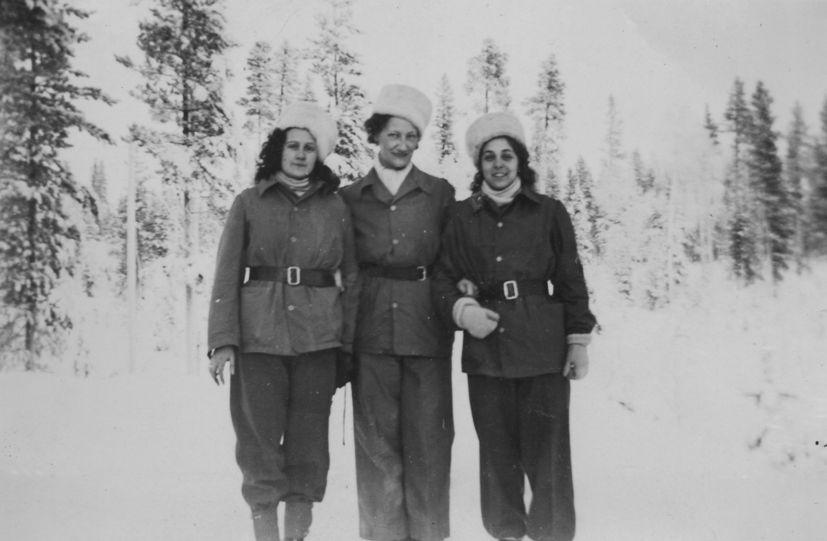 Porträttfoto av tre kvinnliga luftbevakare stående utomhus vintertid, 1942. Klädda i uniform. Från vänster Birgit Johansson, Valborg Holmberg samt Inger (efternamn okänt). Luftbevakarna tillhörde 91:a ls-kompaniet i Tellejåkk, Kåbdalis under beredskapsåren.