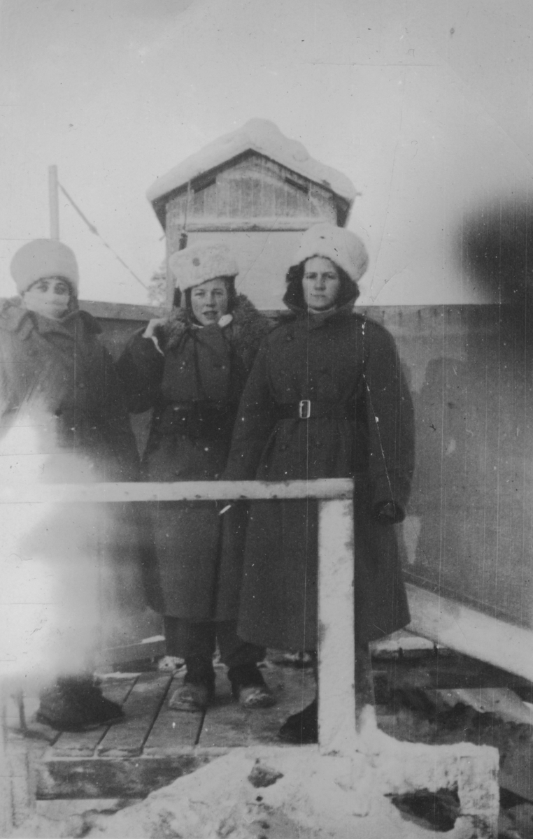 Porträttfoto av tre kvinnliga luftbevakare stående i ett luftbevakningstorn vintertid, 1942. Klädda i uniform och med gevär. Från vänster: Birgit Johansson, Karin Nordberg samt Inger (efternamn okänt).  Luftbevakarna tillhörde 91:a ls-kompaniet i Tellejåkk, Kåbdalis under beredskapsåren.