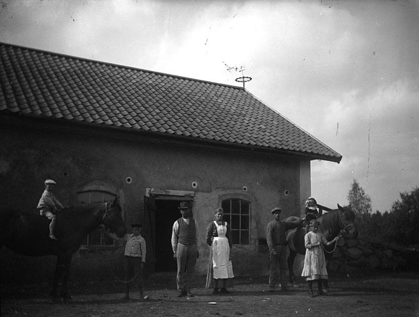 Grupporträtt framför stallbyggnad tillhörig gården i Olsbenning.