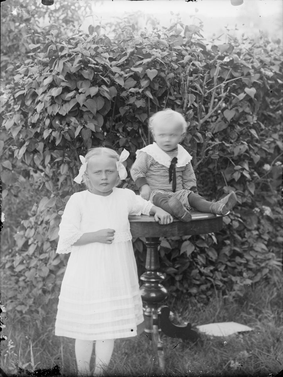 Flicka och pojke i trädgård, Alunda, Uppland
