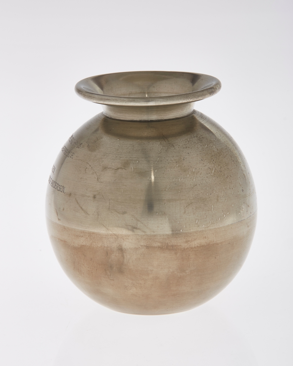 Kuleformet vase med utkraget kant rundt åpning. Inngravert tekst