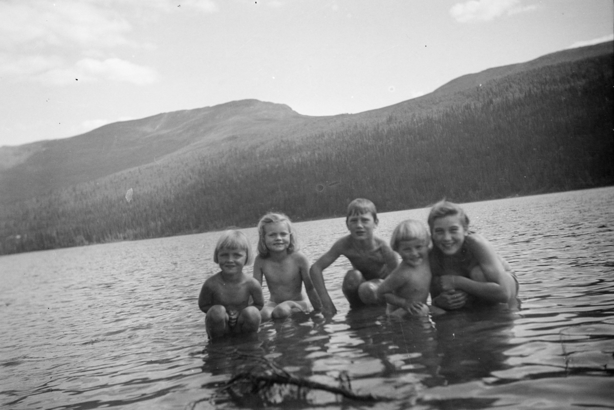 Kvinne og barn bader i fjellvann