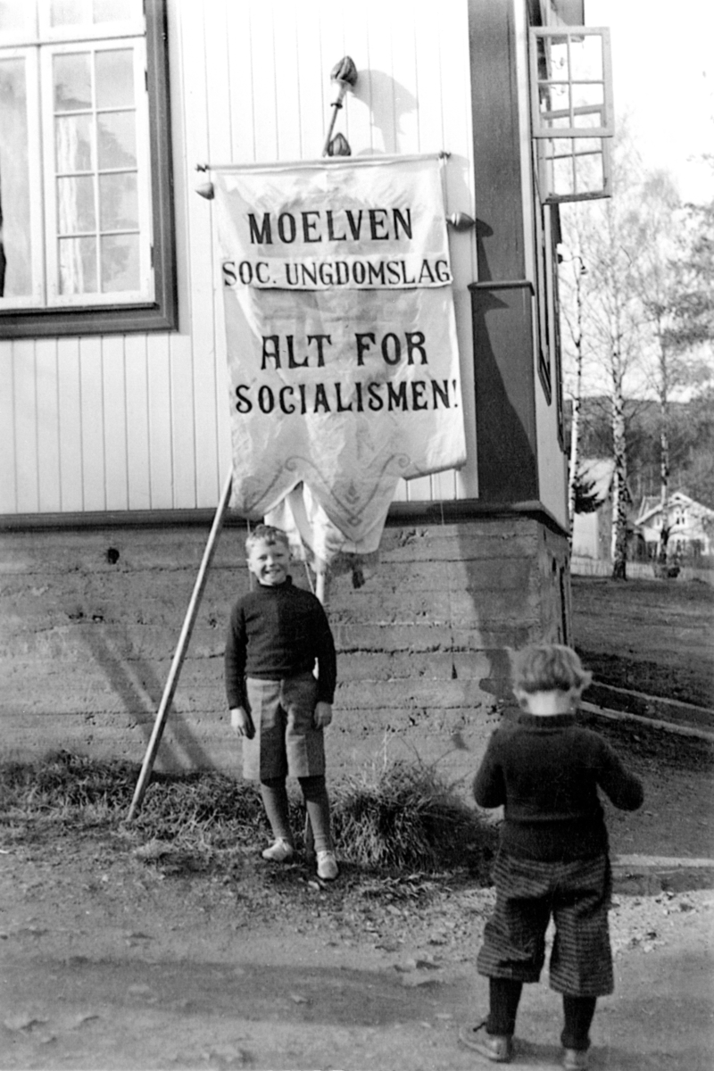 Folkets Hus, Moelv, 1936. Georg Svebakken foran fana til Moelven Socialistiske Ungdomslag med teksten "Alt for socialismen".