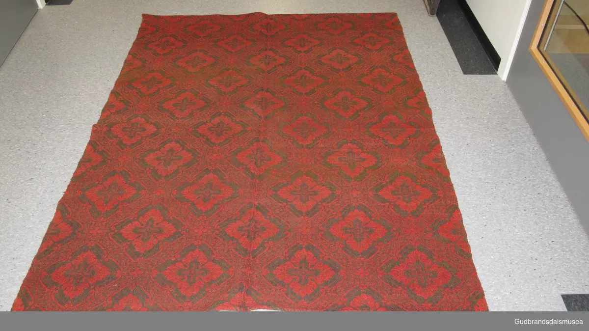 Åkle - i jaquardvev. En form for dobbeltvev. Teppet har samme mønster på begge sider. Farge rødt og sort. Sydd sammen av to like deler. Veven er så avansert at det brukt hullkort.