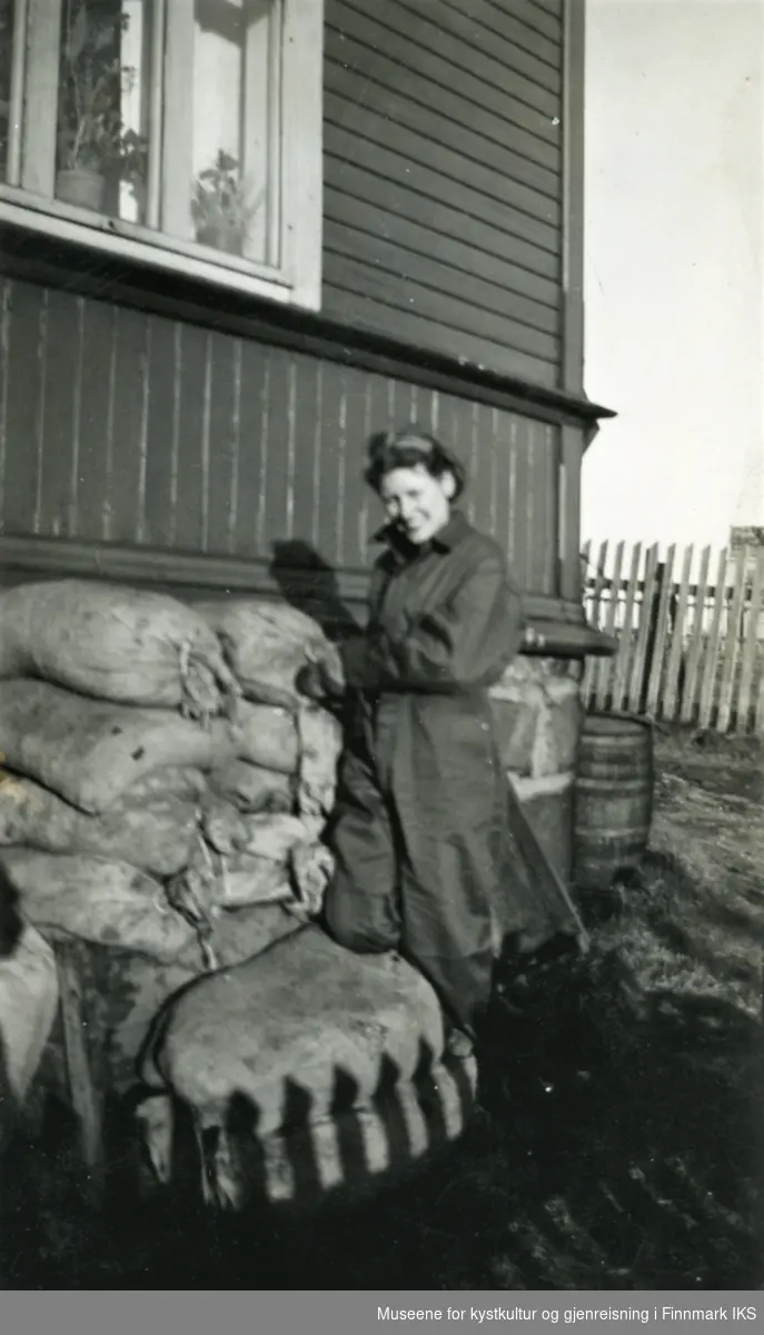 Honningsvåg. Sivilt luftvern. Svanhild Haabeth, f. Hansen, stabler sandsekker rundt huset. 1940.