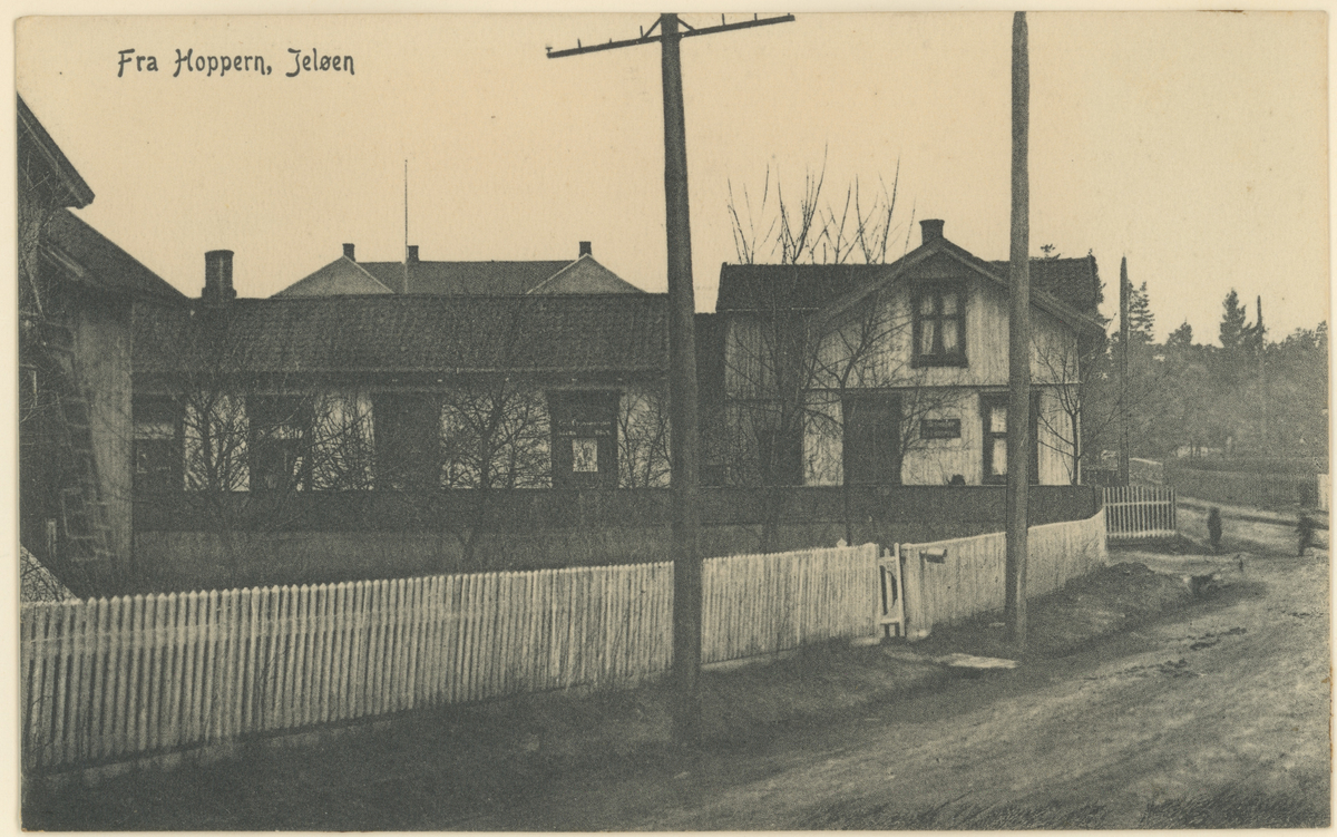 Postkort fra Hoppern, Jeløy, ca. 1910.
Hus vis-á-vis Hydro-Texaco bensinstasjon; i én etasje drev i sin tid fru Aadne Larkollen Hjemmebakeri.
Tekst på bildet: "Fra Hoppern, Jeløen".