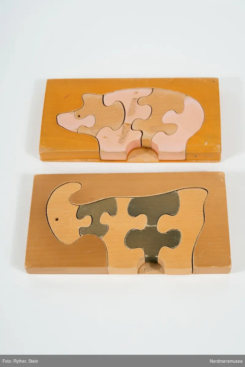 To puslespill, en formet som en gris og en som geit. Grisen har seks brikker, geiten har fem. Brikkene låser seg sammen når alle er plassert på brettet.