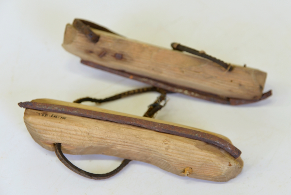 
Ett par skridskor tillverkade av enkla trästycken, skenor av järn och bindslen av smala läderremmar.
