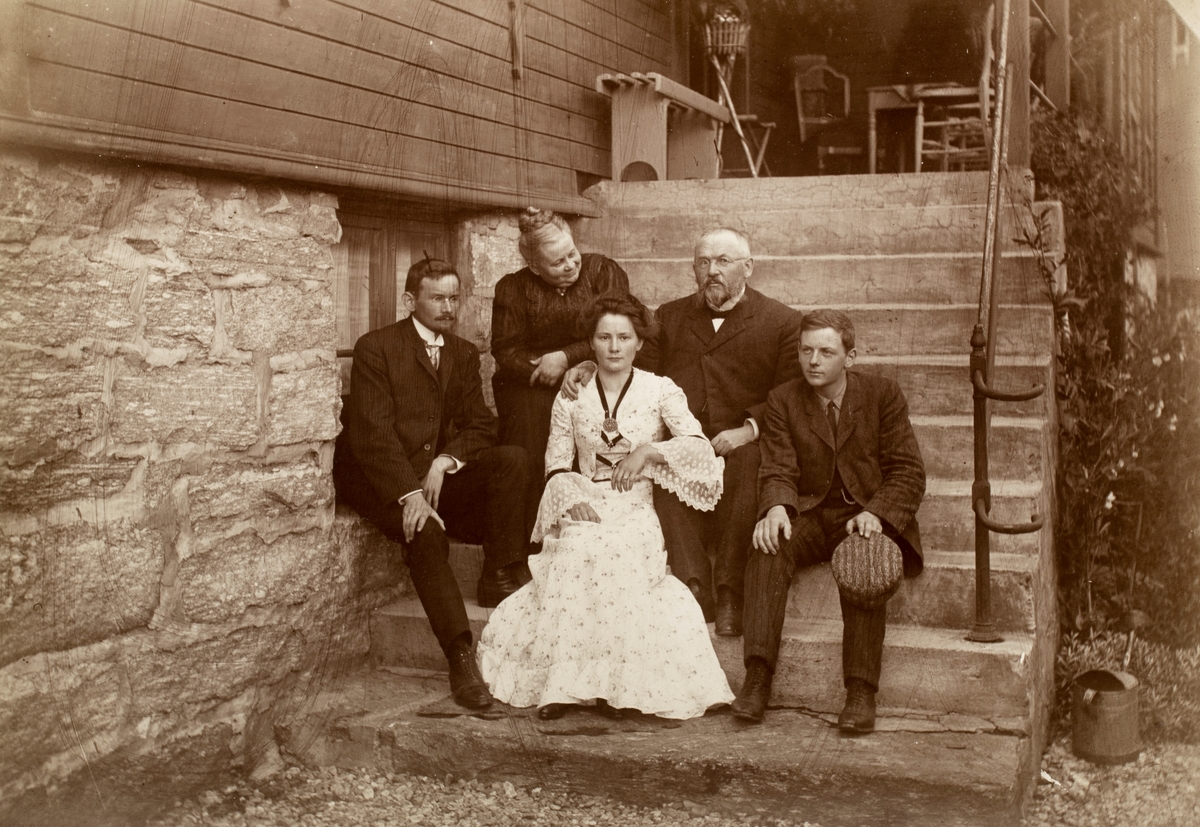 Gruppeportrett av to kvinner og tre menn på trappa utenfor et hus. Noen identifisert som familien Eng.