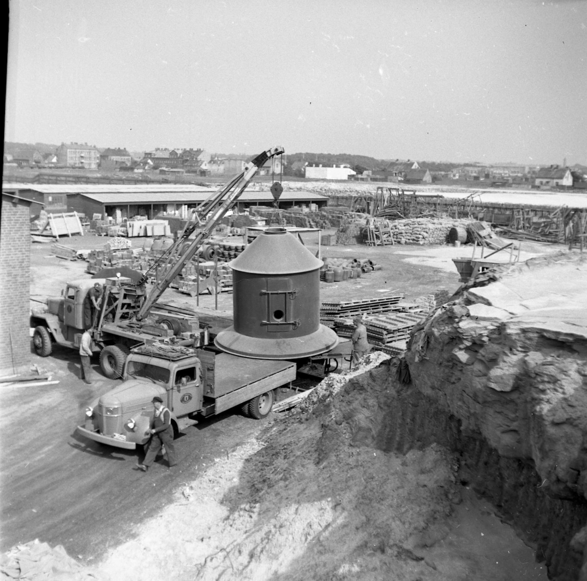 En kranbil lyfter en stor rund cisterna från eller till en lastbil med flak. Det är industridelar till fabriken AB Sprayprodukter som etableras i Gränna 1958.
