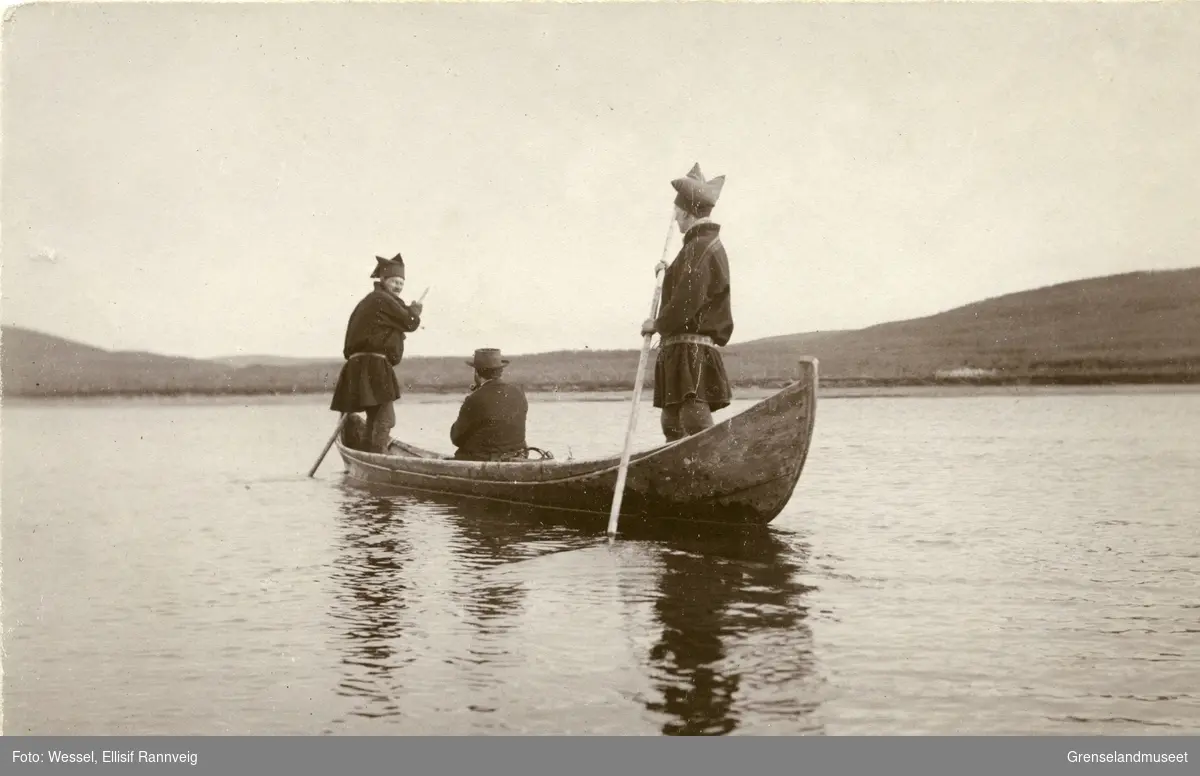 Staking av elvebåt ved Seida, Tana. Andreas Bredal Wessel sitter midt i båten og to ukjente koftekledte menn staker.