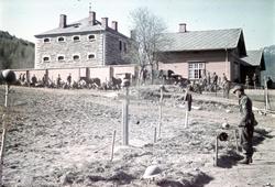 En tysk soldat står foran et jorde med flere graver. Tre av 