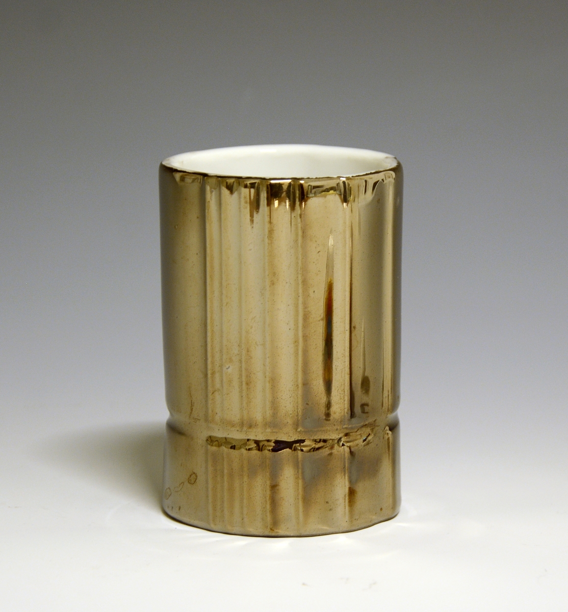 Vase og telysholder av porselen. Fungerer som vase den ene veien og telysholder den andre veien. Sylinderformet med vertikale riller. Horisontal rille litt over bunnen. Hvit glasur. Dekorert i brunt. Ustemplet.
Design: Grete Rønning.