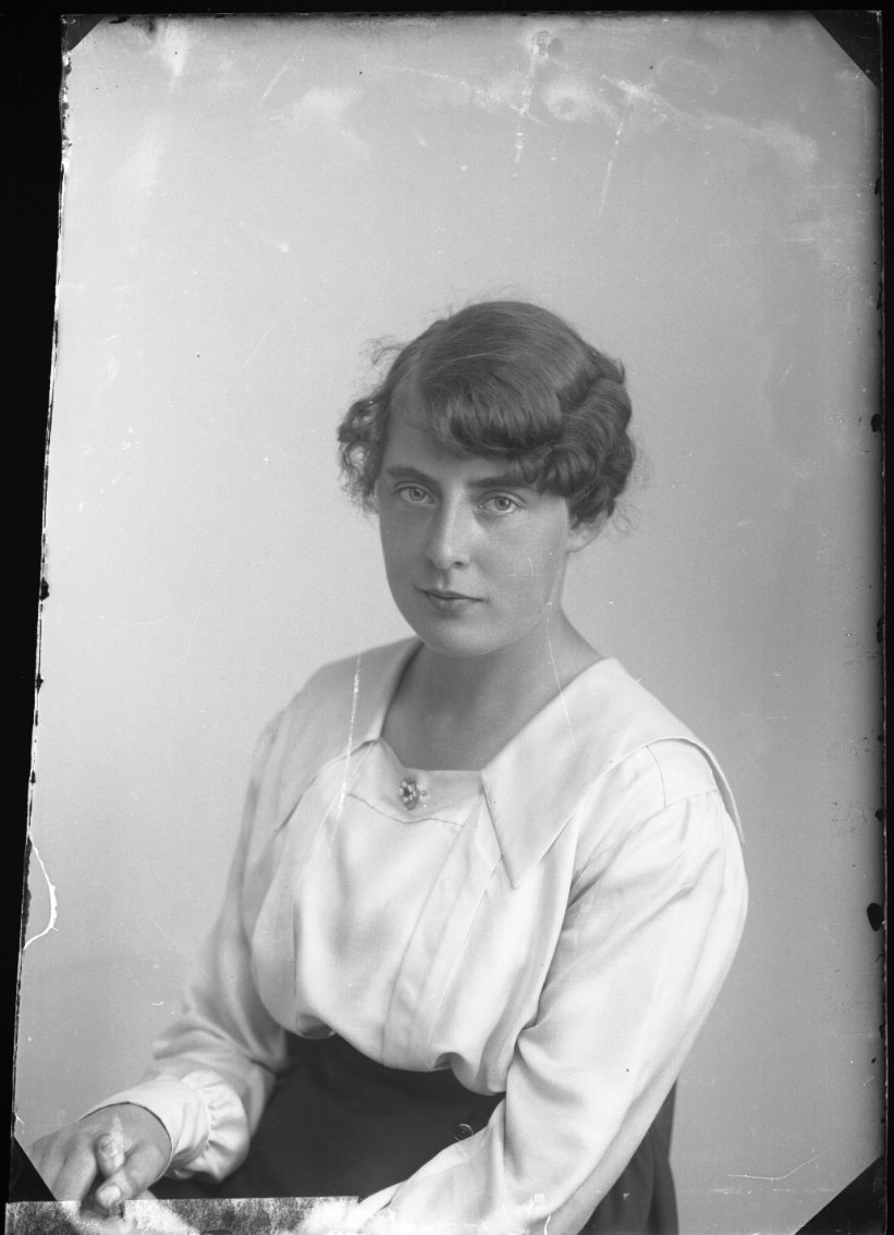 Porträtt av sittande okänd ung kvinna i ljus blus.