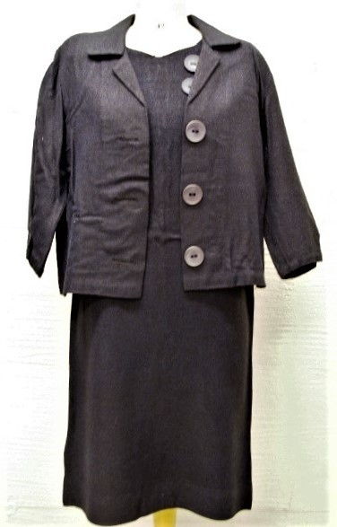 Kjole (a) og tilhørende jakke (b). Kjolen har korte ermer og to store pynteknapper øverst på forsiden. Jakken har tre knapper av samme slag.