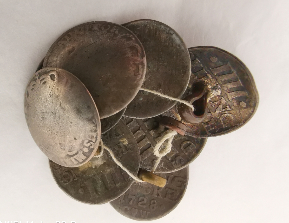 Form: 8 sølvknappar, laga av 4-skillingar (23)
15: frå 1728 og 1730. Kjøpt 20/11 1902 på Høståker i Kaupanger.