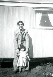 En ung man står tillsammans med en liten flicka framför en b