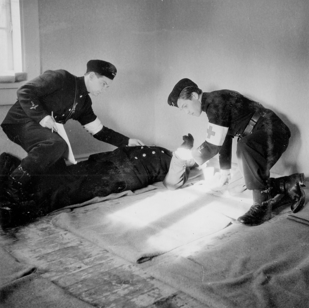 Skadad soldat tas om hand på sjukkvarter vid sjukvårdsövning i fält vid F 11 Södermanlands flygflottilj, 1945. 

Ur fotoalbum "Sjukvårdsskolan 15/1-15/3 1945" från F 11.