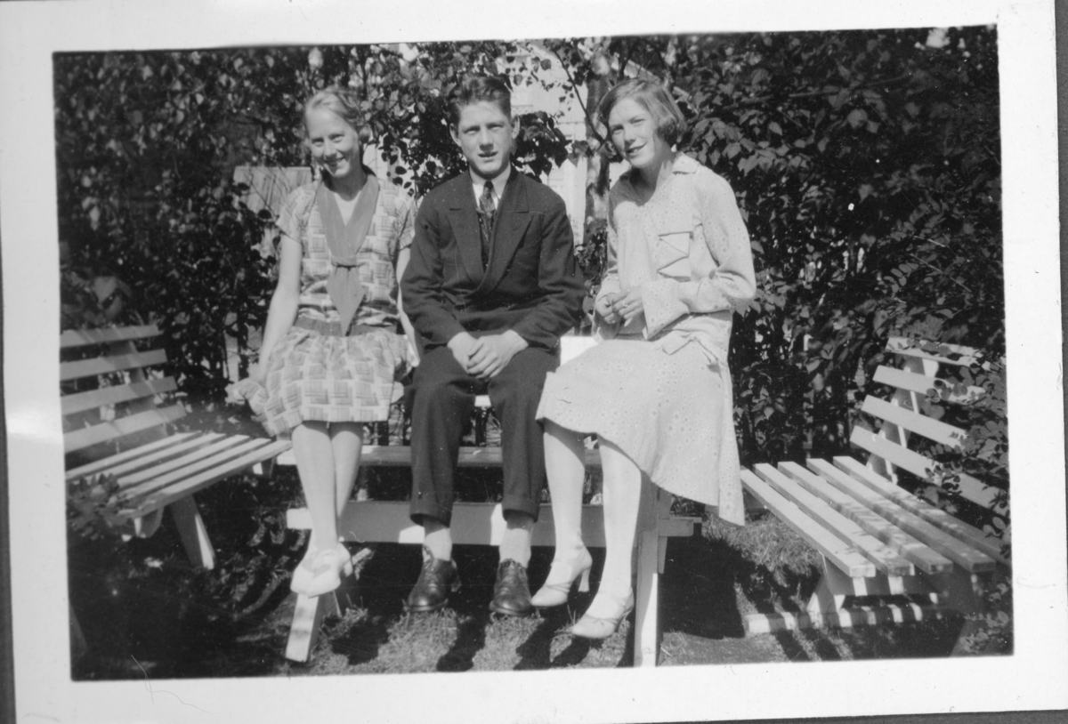 Tre ungdommer sittende på hagebord, to jenter og en gutt. Trolig 1930-tall.