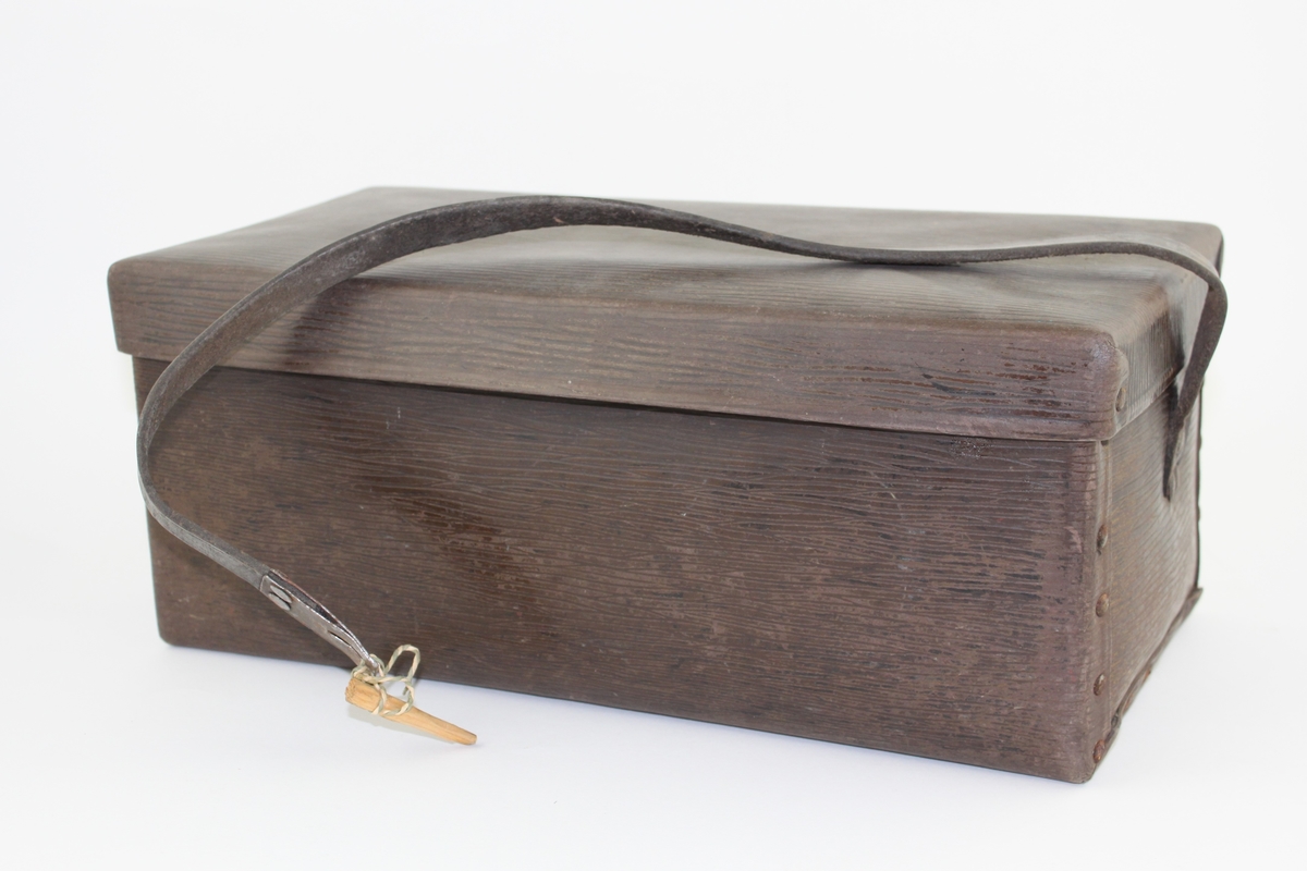 Väska, s k unicabox. Rektangulär låda med lock och bärrem av mörkbrunt konstläder. Egentillverkad låspinne av trä. Använd som matväska under tiden 1920 - 1946.

Vulkaniserat lumppapper: unicafibern