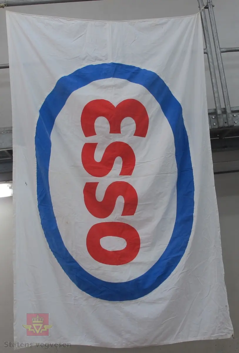 Reklameflagg i hvit tekstil med Esso logo. Flagget består av to sammensydde tekstilbiter med påsydd, ovalt Esso merke på begge sider. Flagget har langsgående sydd kant der det er tredd inn tau til opphenging, og en malje i et hjørne.