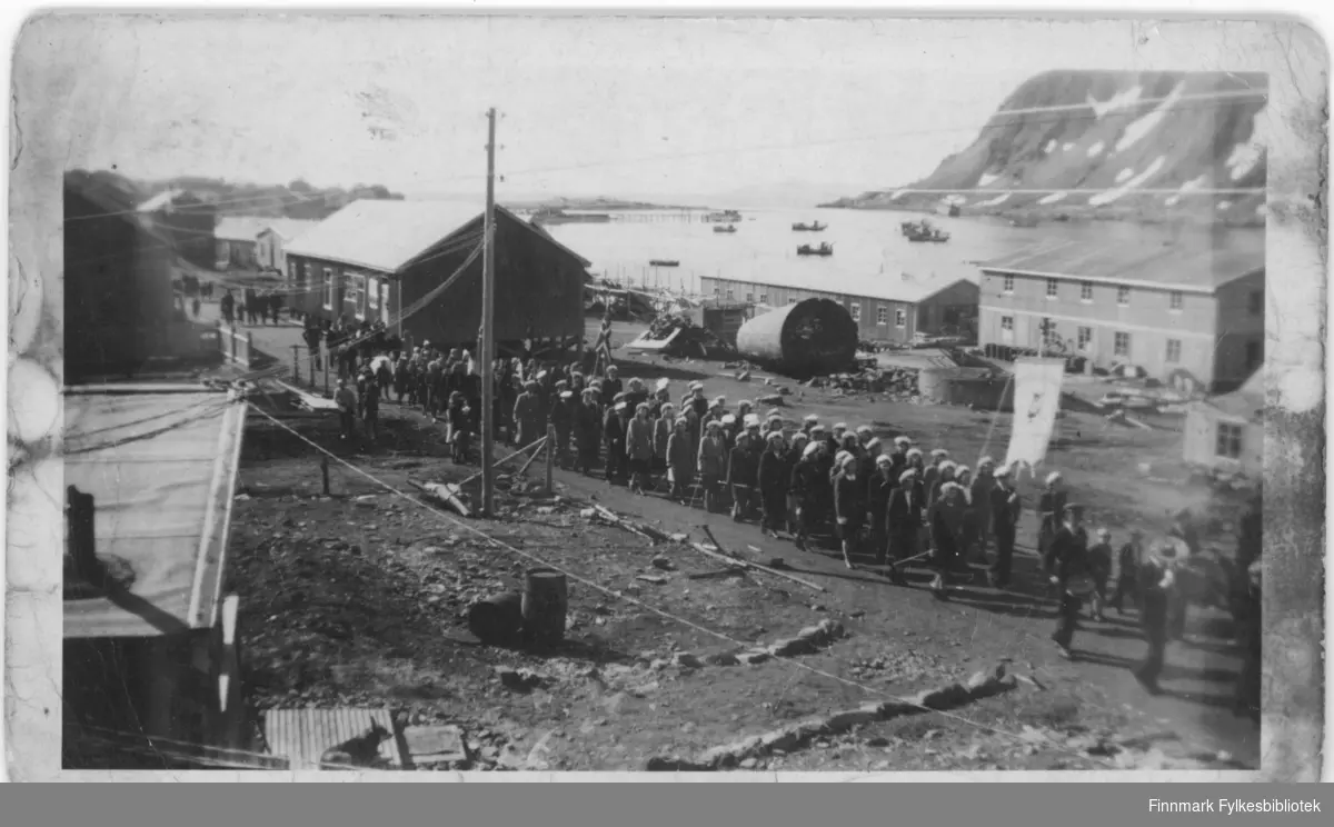 17. mai tog og feiring i Nordvågen i 1948. Vi ser gamle Samvirkelaget, brakka til venstre i bildet. Og Olaf s. Olsens fiskebruk.