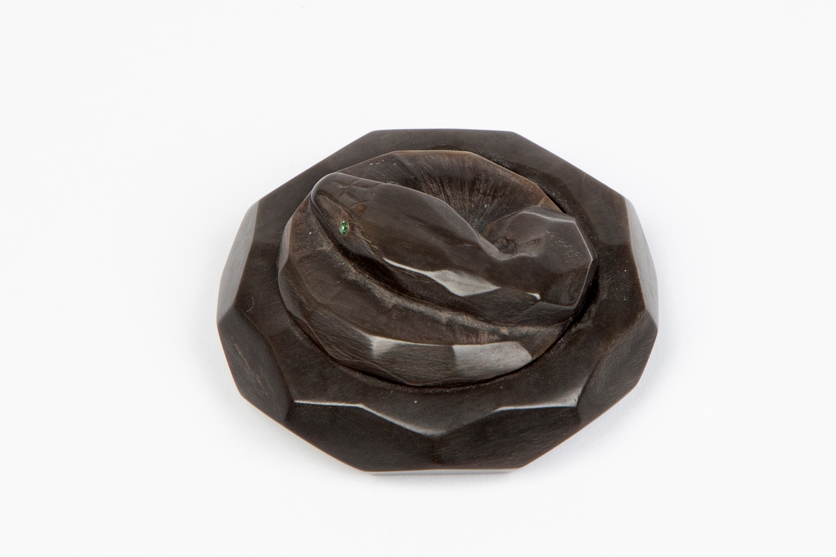 Puddereske i sortfarvet ben, utformet som en sammenkveilet slange med øyne av smaragder.
