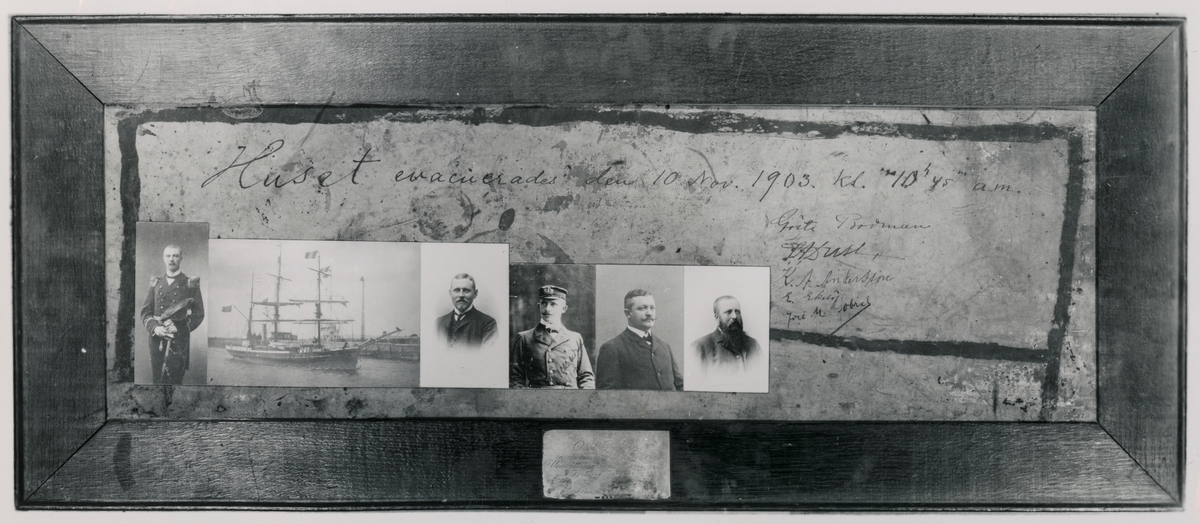 Fotografi av inramat meddelande skrivet på en vaxduk från medlemmar av Otto Nordenskjölds antarktiska expeditions vinterkvarter på ön Snow Hill för att meddela att man räddats av en argentinsk undsättningsexpedition. Texten lyder "Huset evakuerades den 10 november 1903 kl 10h 45 a.m Gösta Bodman, S.A Duse, K.A Andersson, E. Ekelöf, José M Sobral"