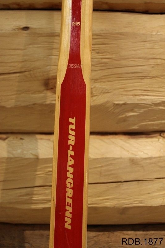 Avsmalende jevnbred ski med liten bue. Bøy uten tupp. Avfaset bakende. 
Dekorert med rød stripe på trehvit bunn.