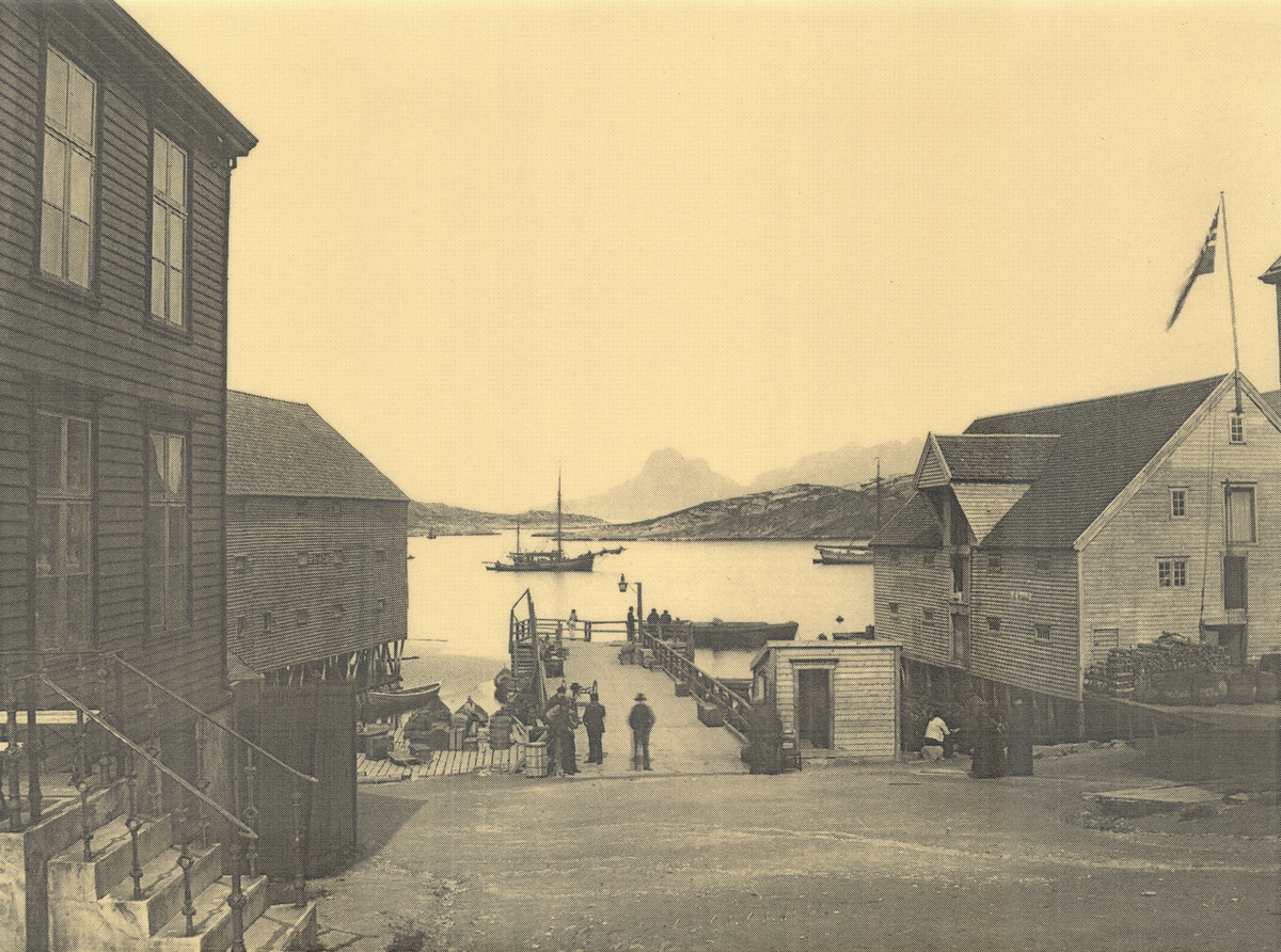 Bodø ca. 1905. Flere personer står på kaia. Utenfor ligger flere seilbåter.