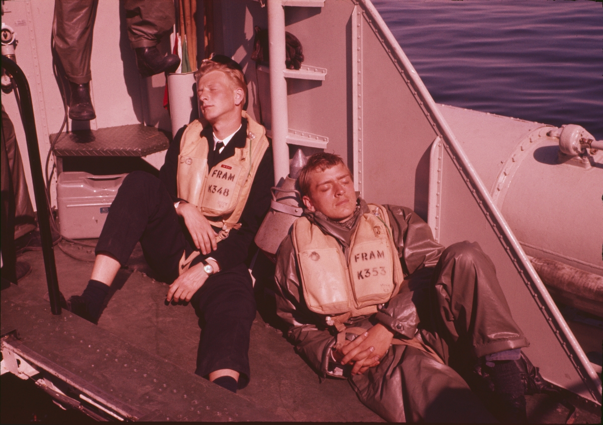 Bilden visar två sjömän med skyddskläder och flytväst som vilar i solsken ombord på T 43.