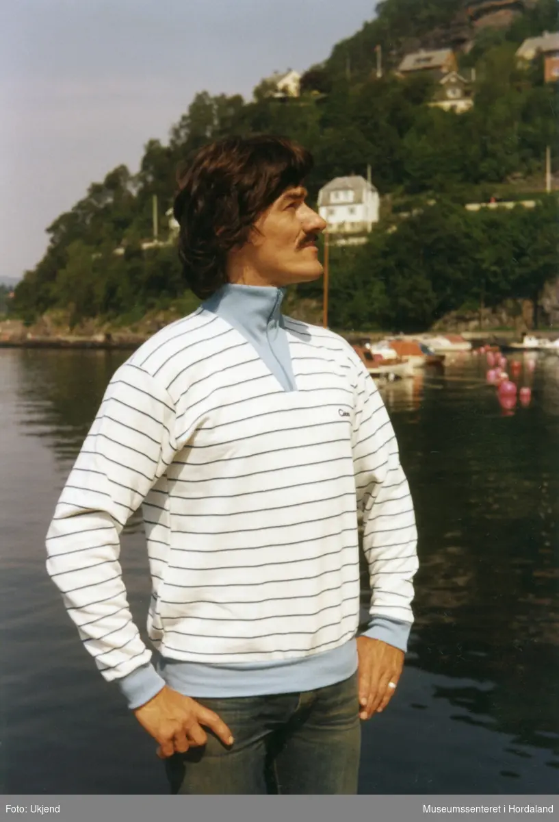 Mann i kvit stripete genser med lyseblå detaljar.