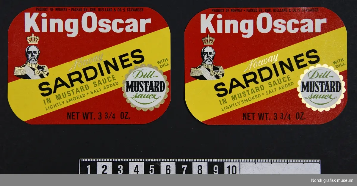 Røde etiketter med et diagonalt bånd i gult over. På venstre side er varnemerkets logo: et portrett av Kong Oscar II. 
På det gule området er varebetegnelsen: 

"Norway sardines in mustard sauce"