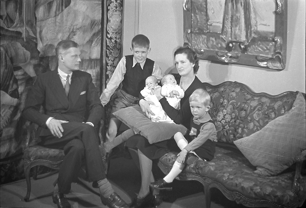 Familien Astrup sitter med to gutter og tvillinger i sofa. Fotografert 1939.