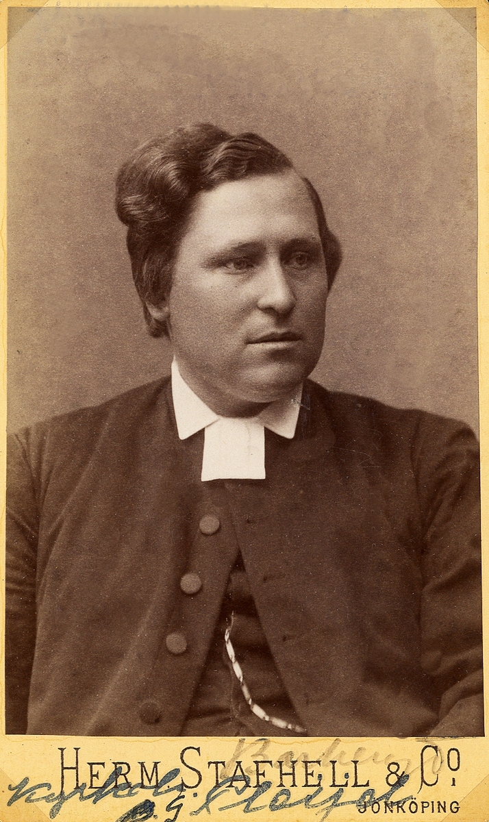 Foto av en man klädd i prästrock och prästkrage. 
Bröstbild, halvprofil. Ateljéfoto.