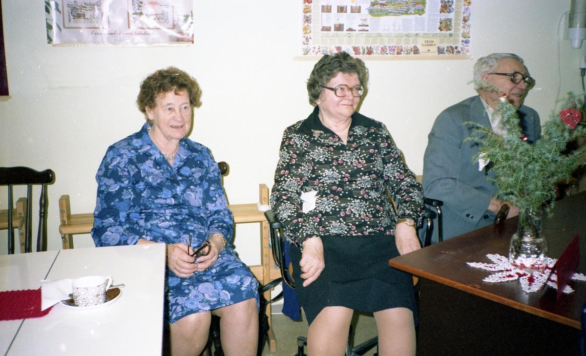 Försäljning av hantverk i pensionärernas hobbylokal på Våmmedalsvägen år 1982. Två kvinnor och en man sitter vid ett bord. Från vänster: 1. Maja Brattberg (1904-2000). 2. Ester Karlsson (1907-2001). 3. Einar.