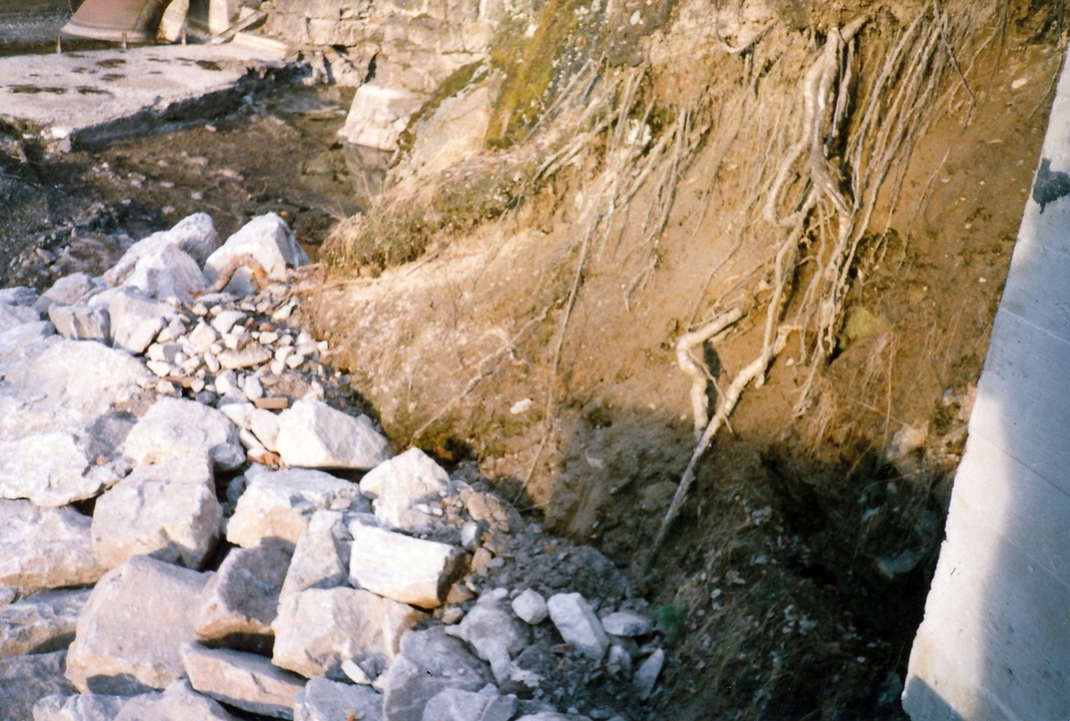 Anleggsområde med stein og jord på nedsiden av kraftstasjonen Kistefos II og det eldste tresliperiet etter Kistefos Træsliberi. Utløp fra en av turbinene i tresliperiet synlig i bakgrunnen.