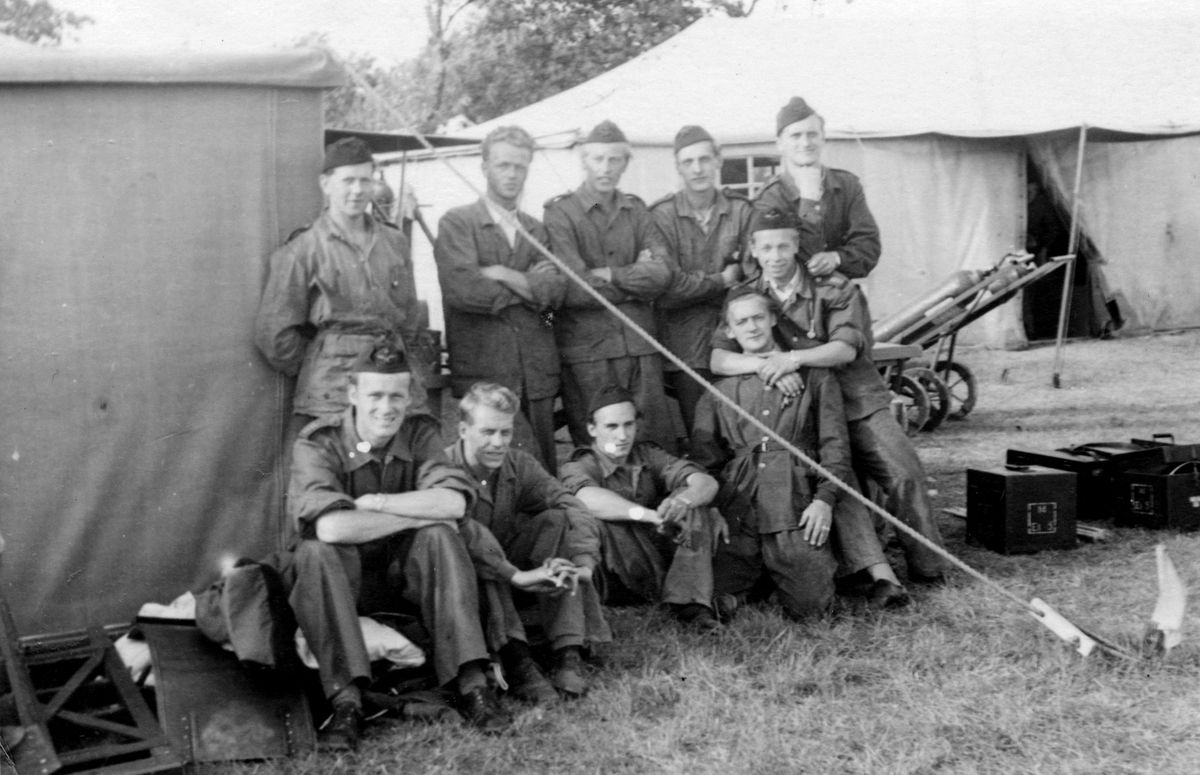 Grupporträtt av militära flygmekaniker, 1940-tal. Tio män vid en tälthangar.