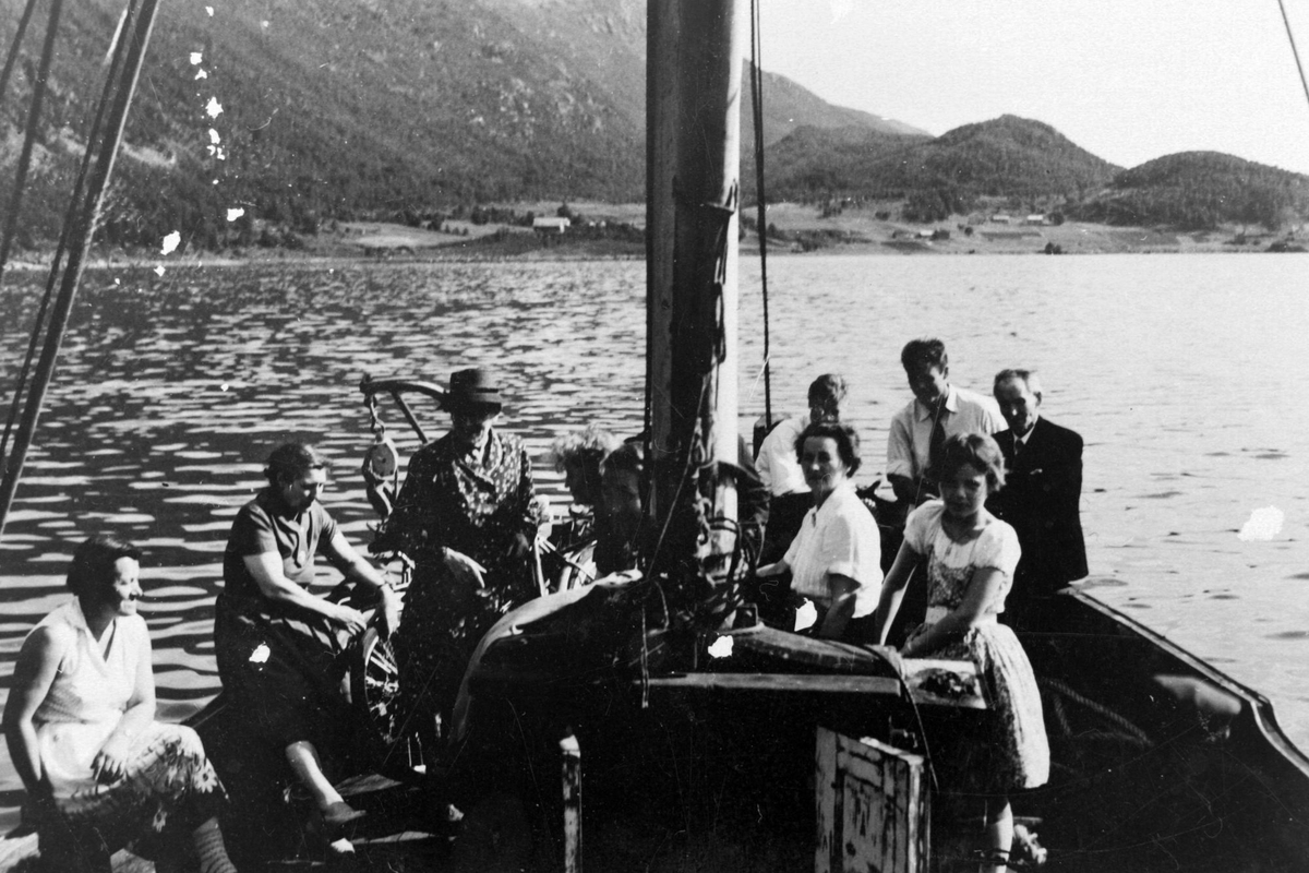 Folk ombord i båten "Bara". Gården Gullholm i bakgrunnen.