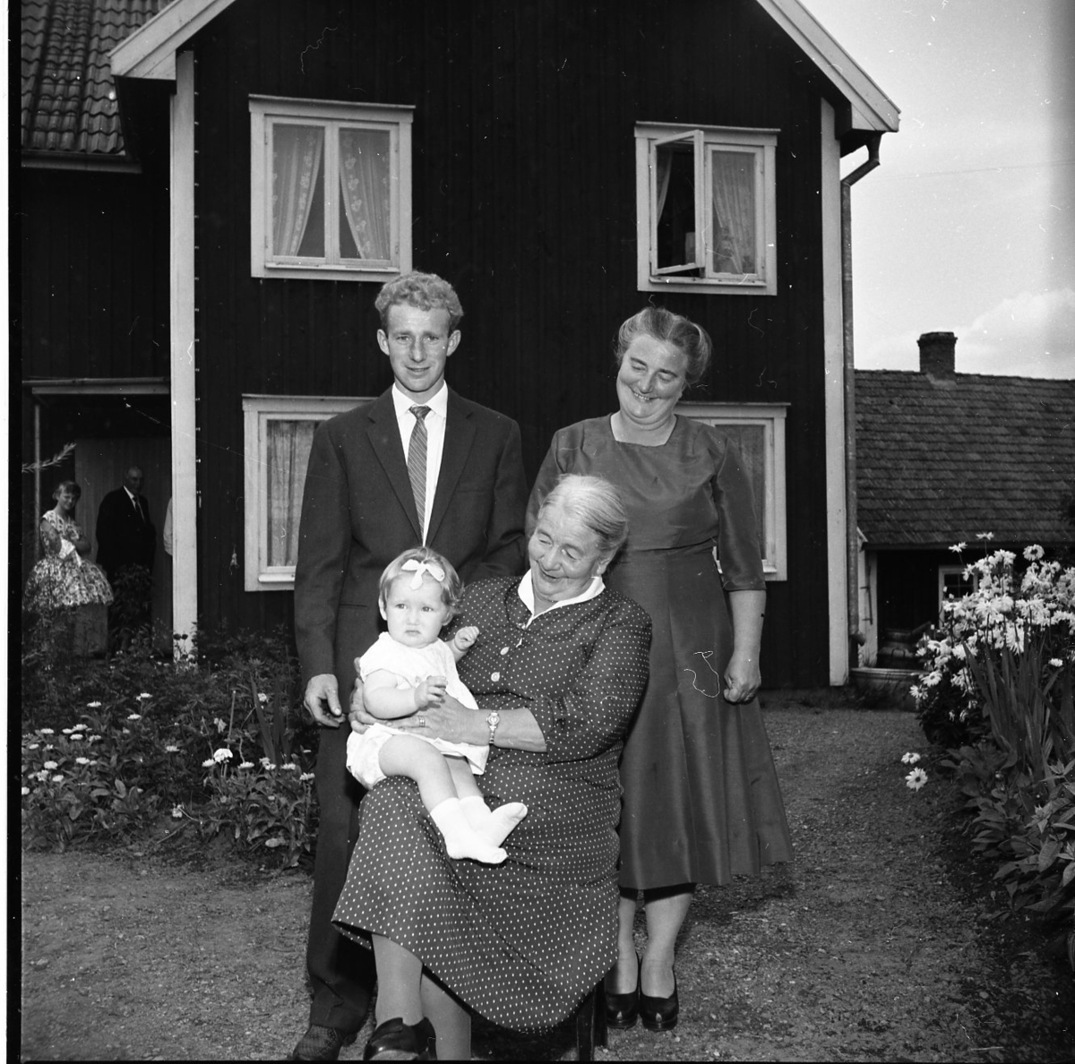Fyra generationer samlade på gårdsplan till en fastighet i Kaxtorp. Ester Karlsson sitter med en liten flicka i knät. Bakom henne från vänster står hennes barnbarn Sten Egon Granstrand och dottern Britta Granstrand.