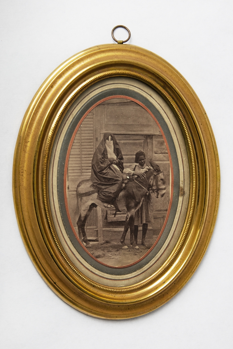 Beslöjad egyptisk kvinna ridande  på en åsna i basaren i Kairo. Litet fotografi i ram.

Tillhör Adolf Andersohns samling.

Johan Adolf Andersohn (1820-1887) var handlare/filantrop och museets grundare.